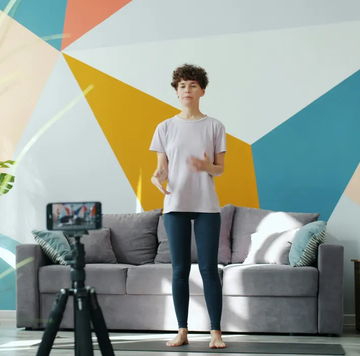 A fitness creator filming a workout video on a phone tripod at home